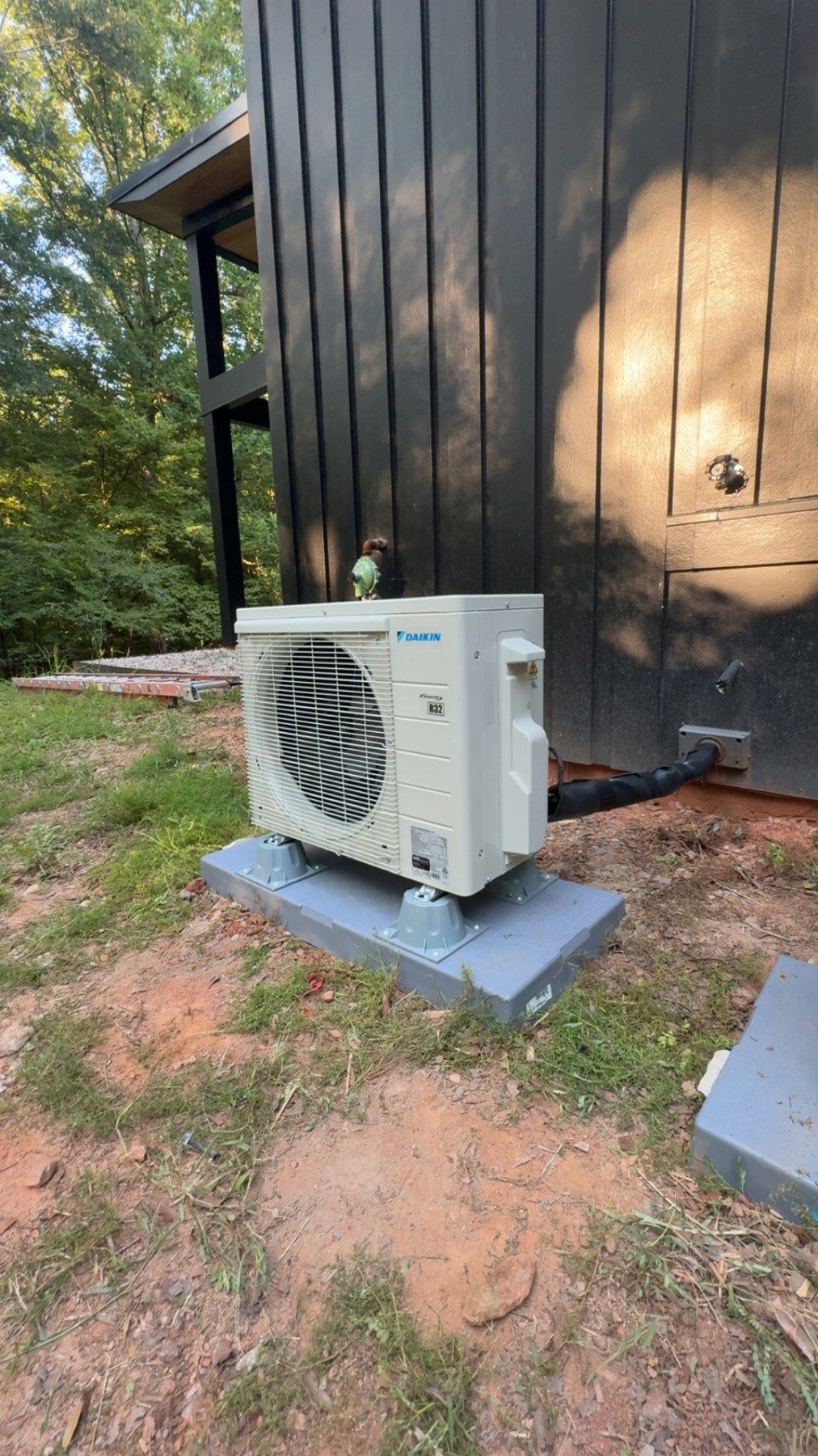 Outdoor unit installed beside a home with dark siding